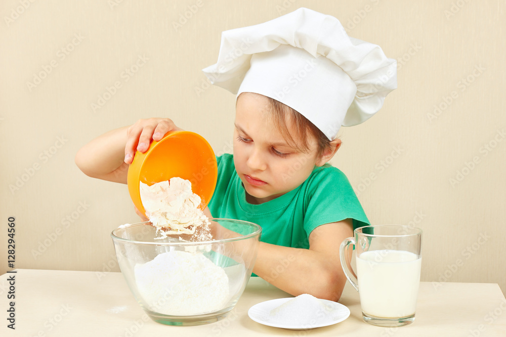 Little funny chef pours flour for baking the cake Little funny chef pours flour for baking the cake