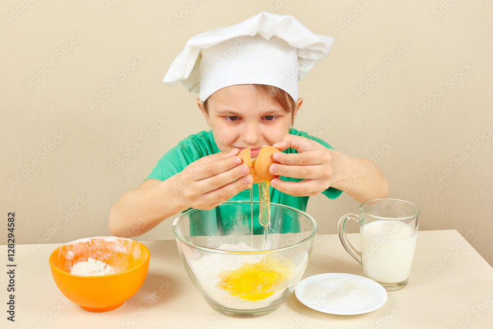 Little funny chef pours eggs for baking the cake Little funny chef pours eggs for baking the cake