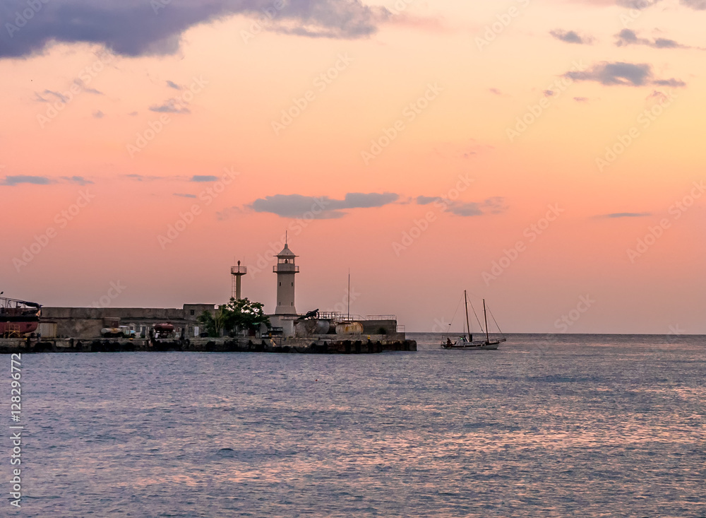 The lighthouse at the seaport of Yalta on the sunset background