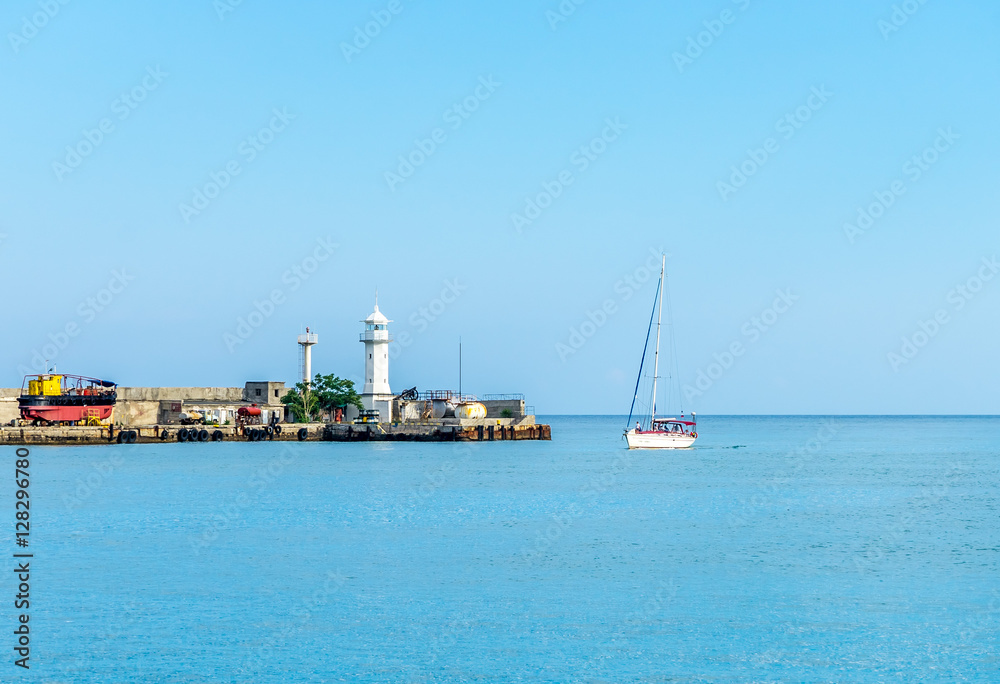 Lighthouse and yacht entering the bay