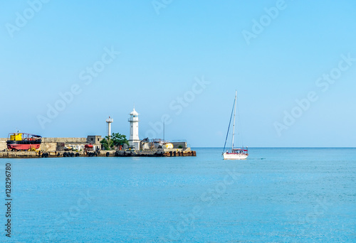 Lighthouse and yacht entering the bay © den781