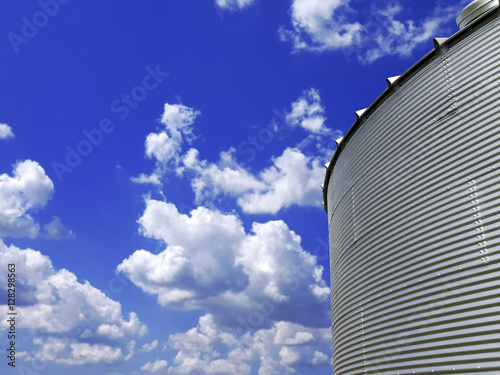Low angle view of metal grain bin with blue sky in the background 