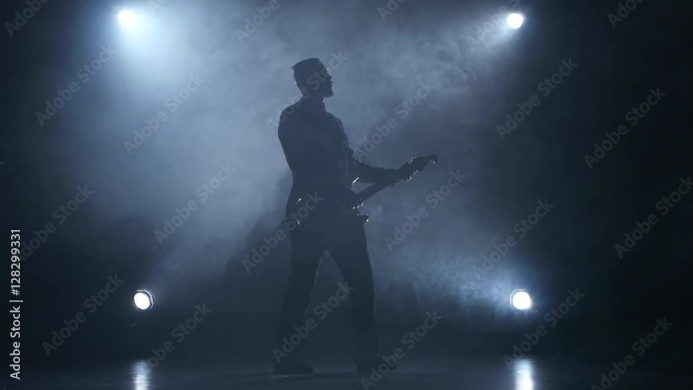 Guitarist in slow motion plays electric guitar. Smoke background. Studio Guitarist in slow motion plays electric guitar. Smoke background. Studio