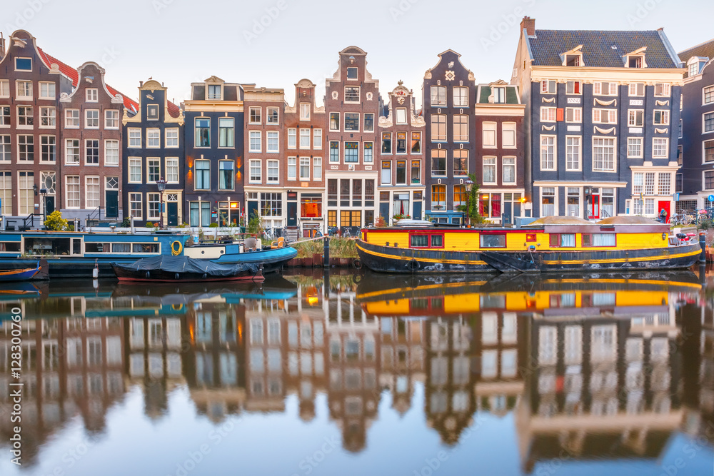 Obraz premium Kanał Amsterdam Singel z typowymi holenderskimi domami i łodziami mieszkalnymi w porannej niebieskiej godzinie, Holandia, Holandia.