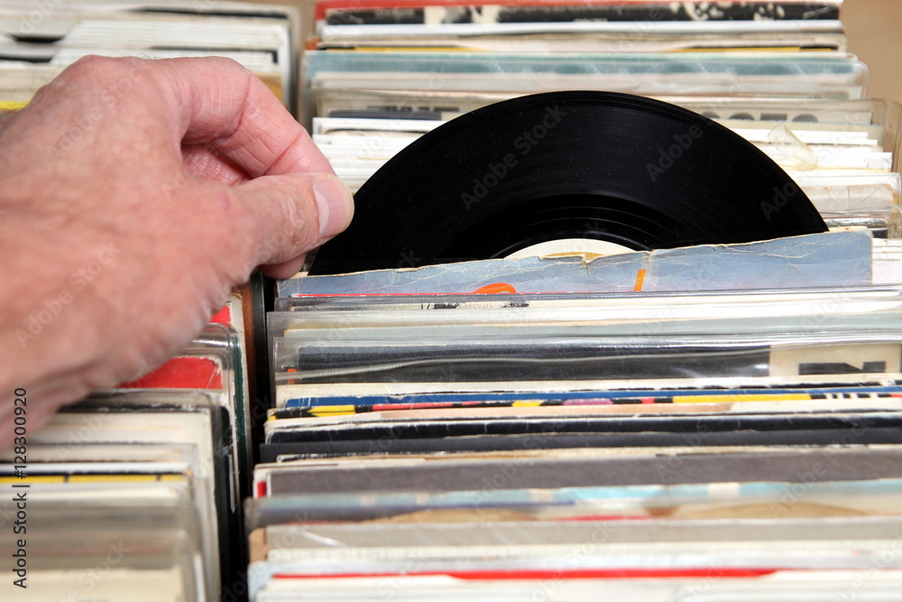 Hand of a man looking at vinyl 7" single 45 records for sale at a retro record fair Stock Photo | Adobe Stock