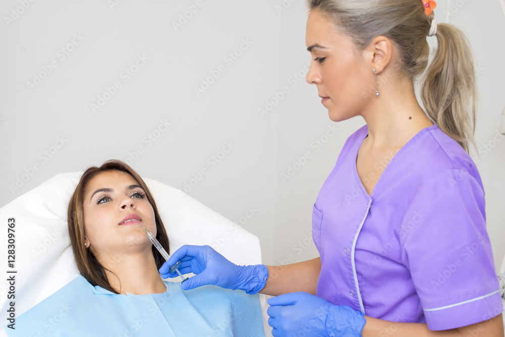 Fototapeta premium Young Woman Geting an Injection in her Lips in Beauty salon.