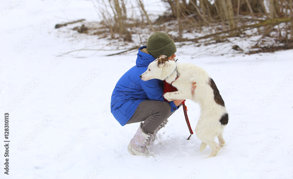 Young woman with her dog on the snow in winter.Girl hugging dog.Woman outdoors with her cute dog having fun./Girl with dog in winter park