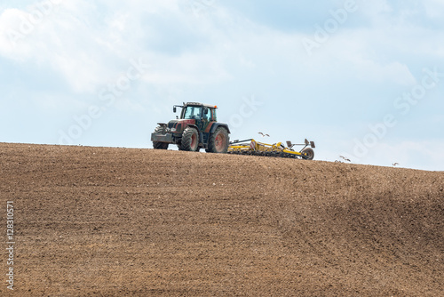 Large view on the tractor harrowing the field in spring season