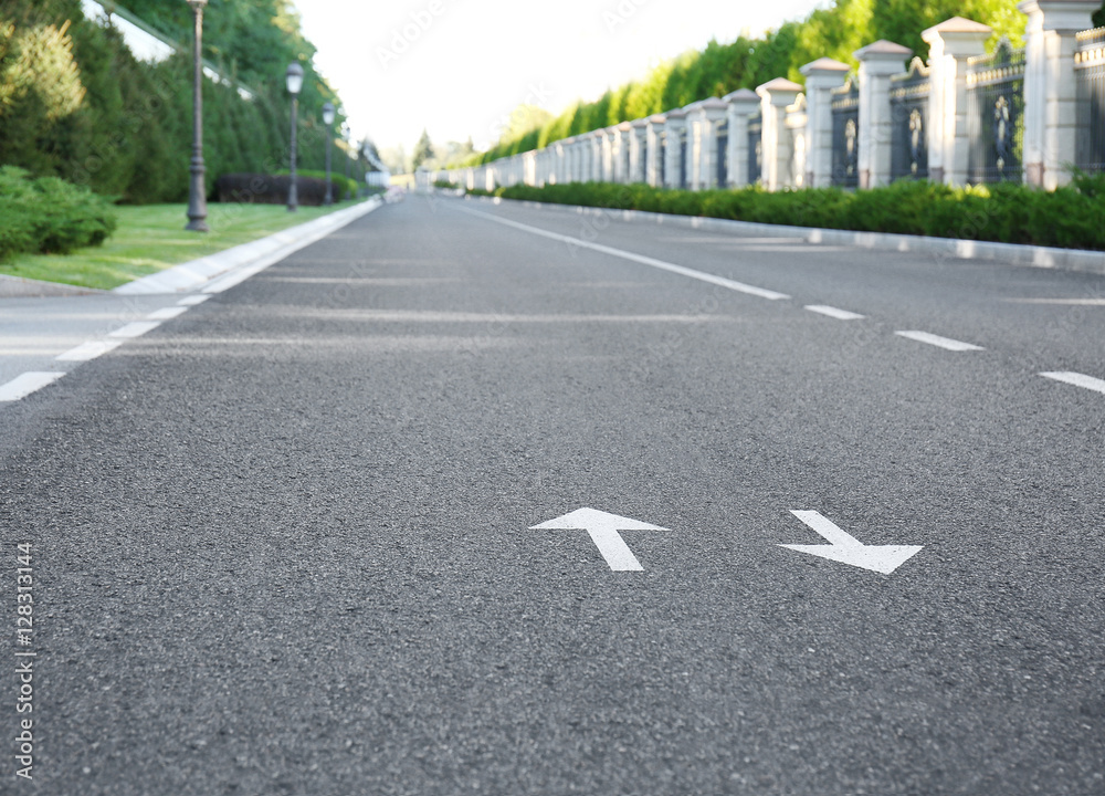 Obraz premium Arrow signs on asphalt road showing direction of movement