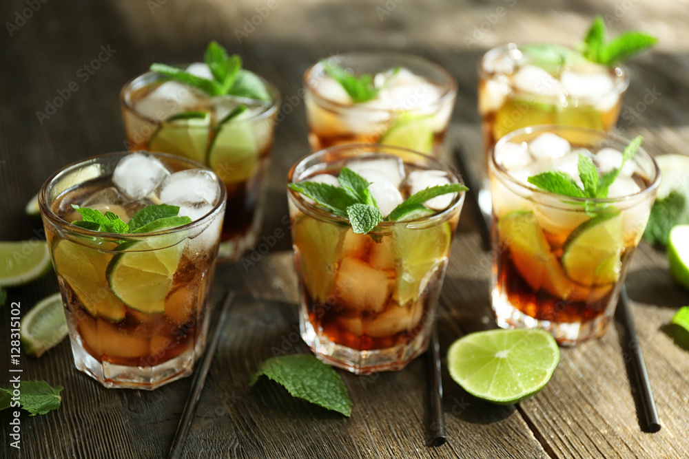 Glasses of cocktail with ice and mint on wooden table closeup Glasses of cocktail with ice and mint on wooden table closeup