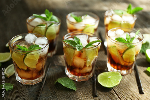 Glasses of cocktail with ice and mint on wooden table closeup