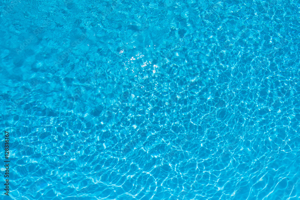 Ripple blue water surface in swimming pool with sun reflection