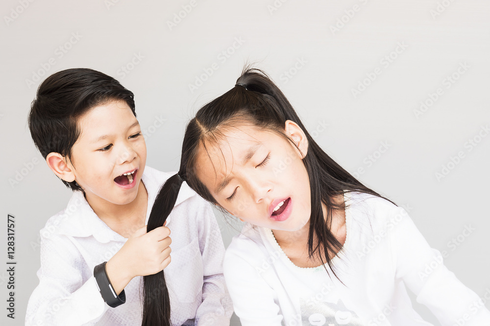 Lovely Asian couple school kids playing together, 7 and 10 years old, over gray background Lovely Asian couple school kids playing together, 7 and 10 years old, over gray background