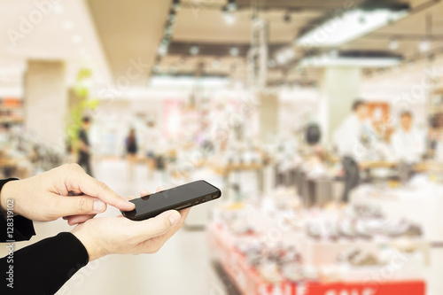 Εκτύπωση καμβά Man using mobile phone over blurred superstore background