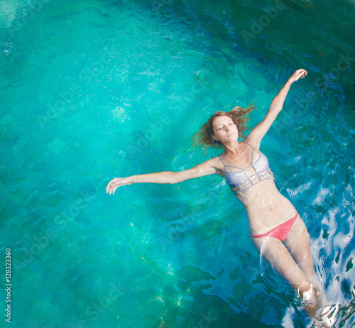 Young woman relaxing in the pool   © triocean