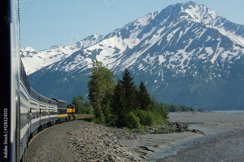 Train rounding bend in front of snowy mountain