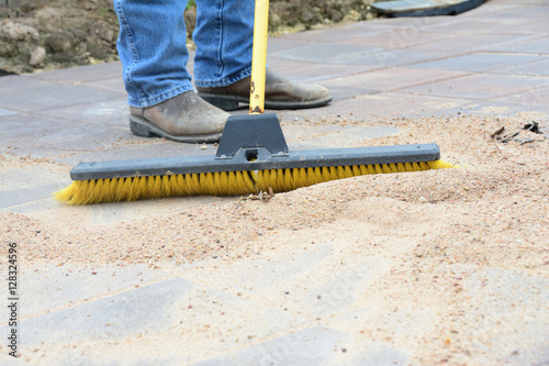 Man pushing broom to grout tile