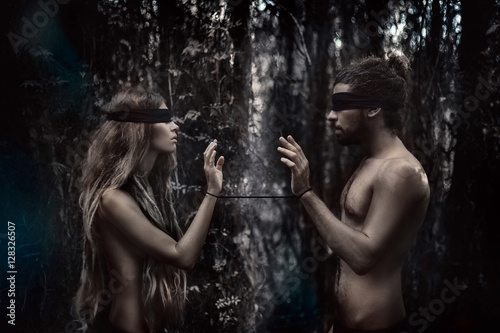atrractive young man and woman with eyes closed. lost in forest photo
