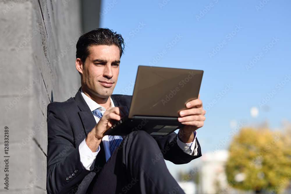 Businessman using a laptop computer sitting in the street