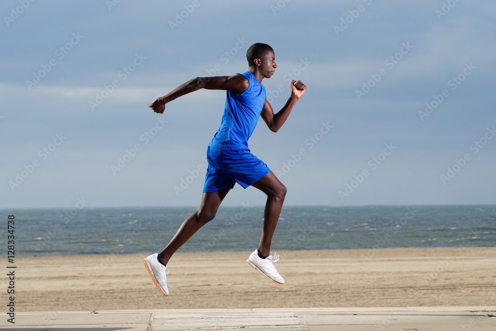 Fit young african man running along the beach Fit young african man running along the beach