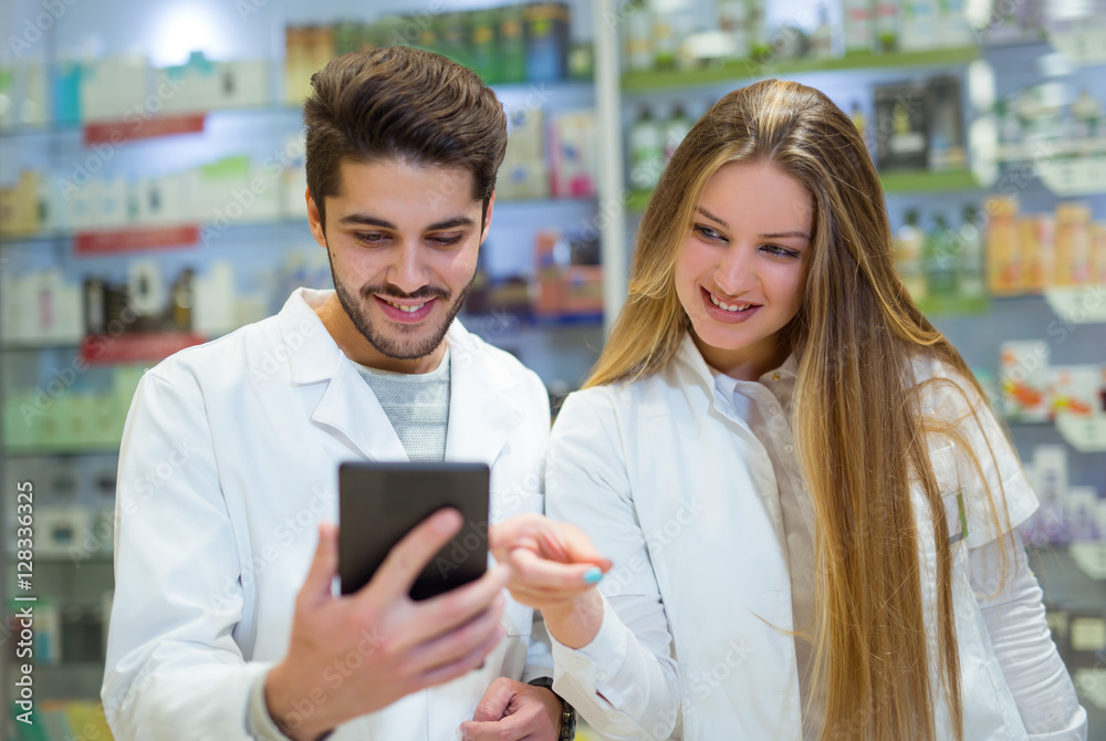 Pharmacists using digital tablet while checking medicine in pharmacy