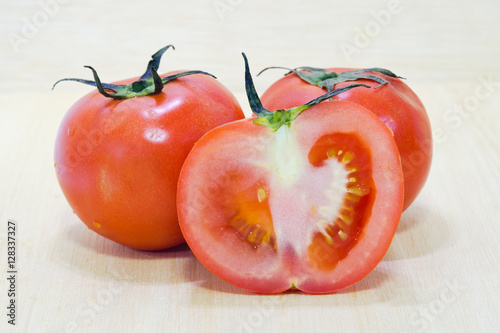 Tomato fruit with half cross section isolated on wooden backgrou photo