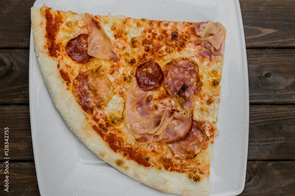 Slice of fresh pizza on dark brown table background, close up