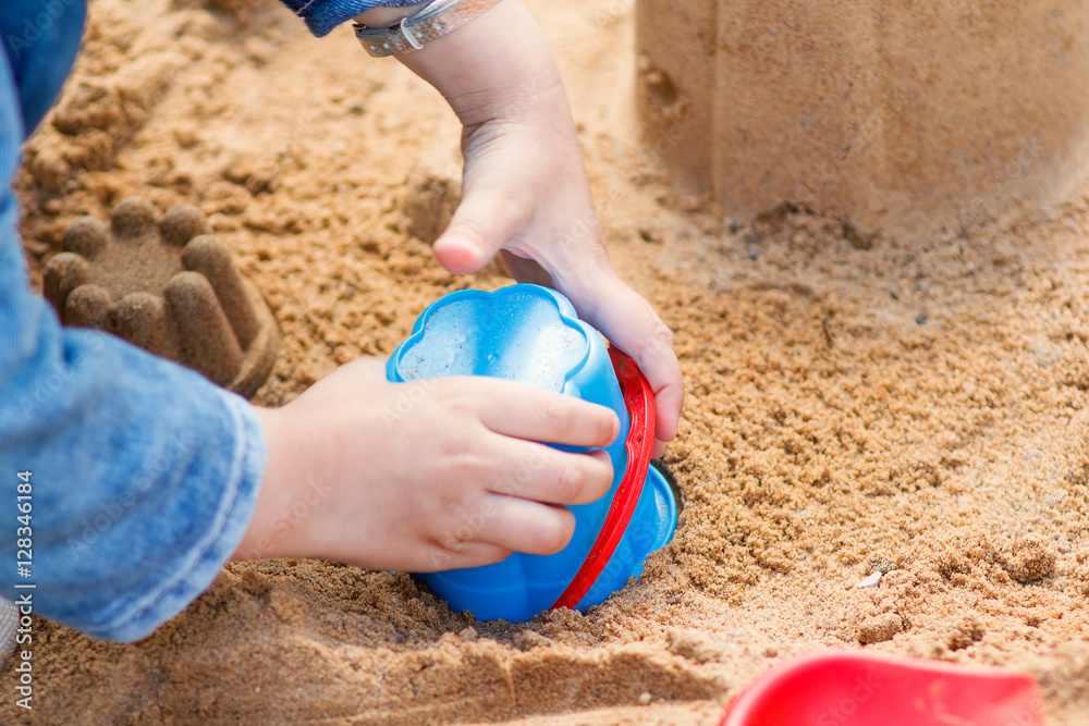 Child hand make cake out of the sand close up Child hand make cake out of the sand close up