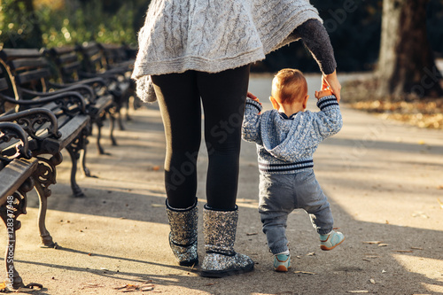 Mom teaching her son's first baby steps in the park photo