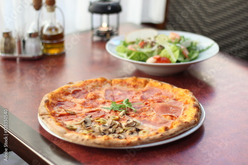 Restaurant food with fresh ingredients - salami pizza and salad with shrimps, parmesan and olive oil