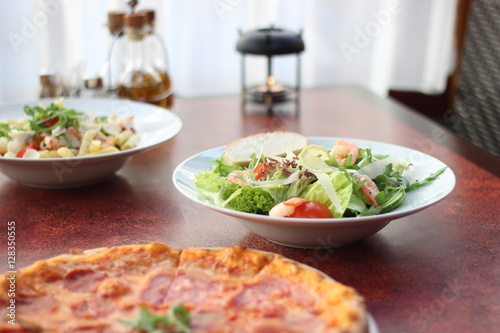 Restaurant food with fresh ingredients - salami pizza and salad with shrimps  parmesan and olive oil