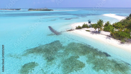 Panoramic landscape seascape aerial view over a Maldives Male Atoll island. Empty white sandy beach with lifeguard tower seen from above