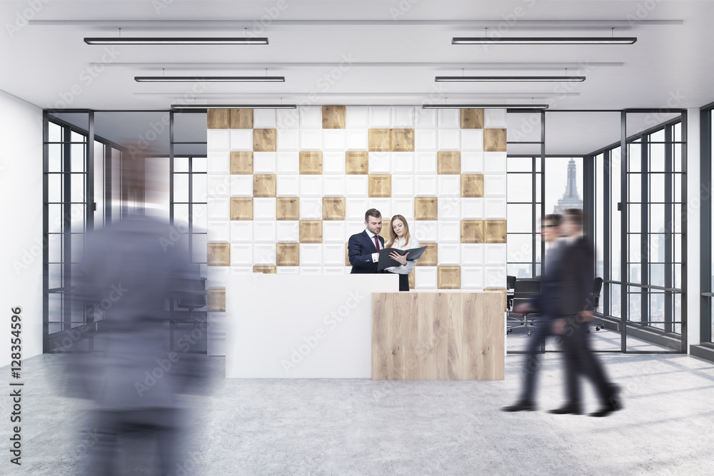 People in the office lobby with tiled white and wooden wall