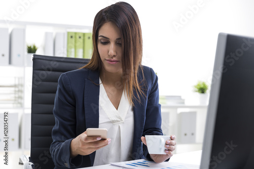 Businesswoman with her cell phone and a cup of coffee