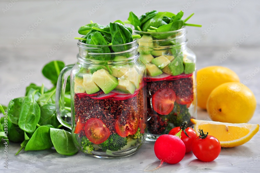 Healthy salad with quinoa, avocado, tomato, red onion, baby spinach, radish and olive oil in a Mason jars. Healthy salad with quinoa, avocado, tomato, red onion, baby spinach, radish and olive oil in a Mason jars.
