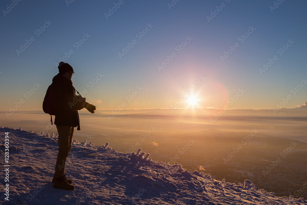 Male photographer on the mountain top. Sunset, winter. Snowy.