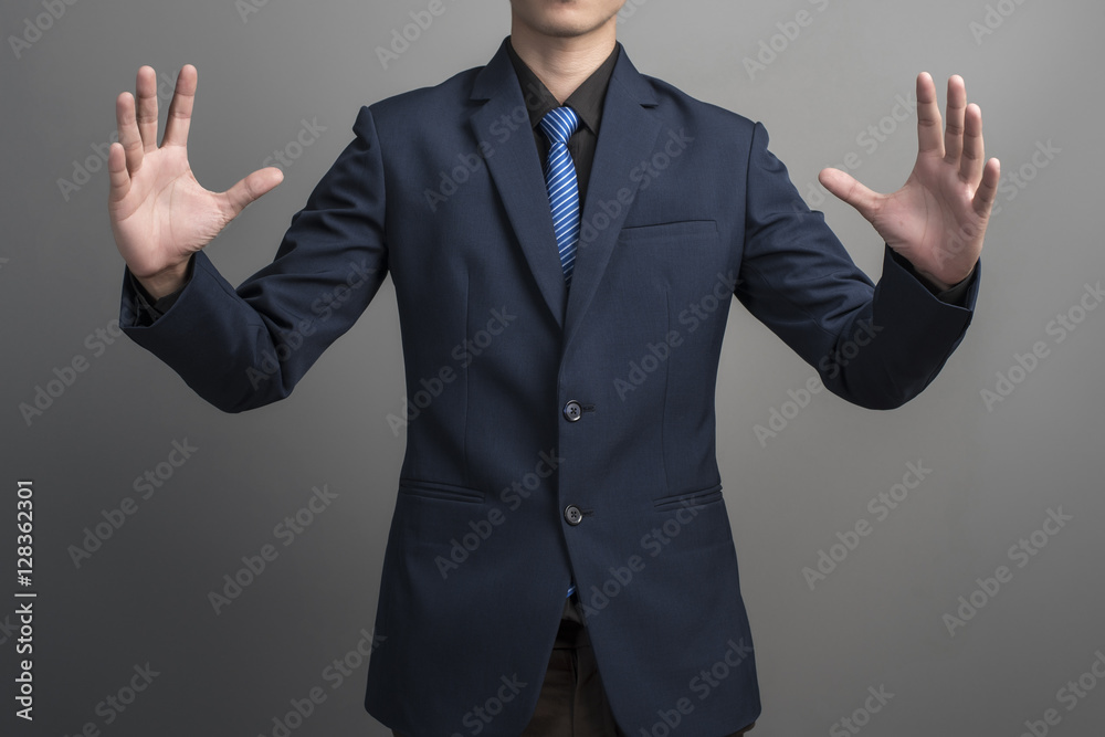 Close up of businessman in blue suit holding something on gray b Close up of businessman in blue suit holding something on gray b