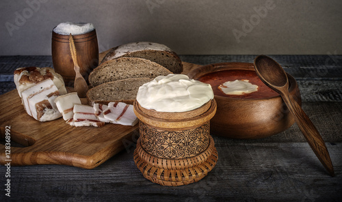 Obraz na płótnie bowl of soup with sour cream, bread and bacon on wooden table w salonie