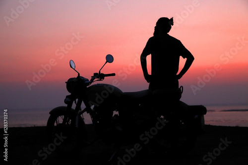 Young man standing near motorbike and enjoying sunset view  © Rahul