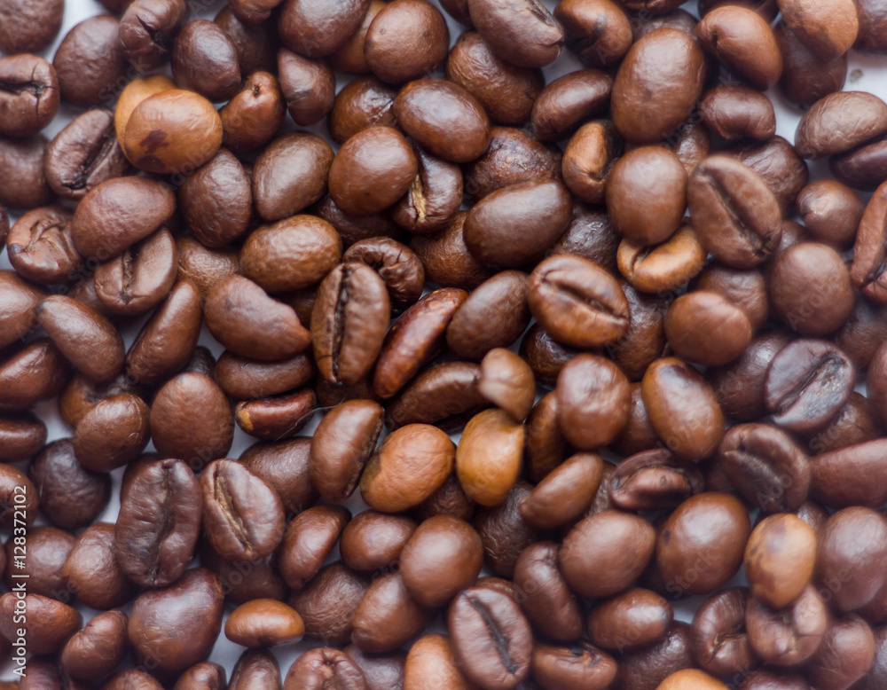 Close up beans on a white background. Coffee on the entire screen for the background. Roasted coffee beans brown. Lots of coffee in high definition. Close up beans on a white background. Coffee on the entire screen for the background. Roasted coffee beans brown. Lots of coffee in high definition.