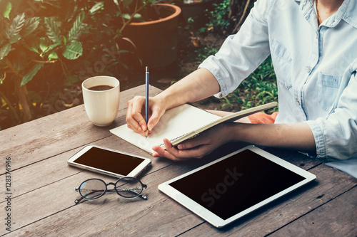 Young business woman hand with pencil writing on notebook. Woman