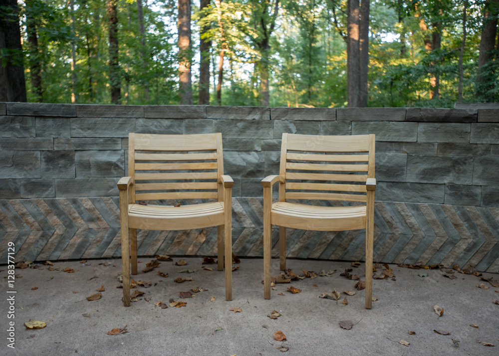Two Wooden Arm Chairs Against Stone Wall Two Wooden Arm Chairs Against Stone Wall