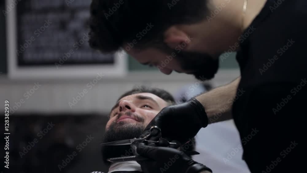 Hairstyling process. Close-up of a barber cutting beard of a young male client. Hairstyling process. Close-up of a barber cutting beard of a young male client.