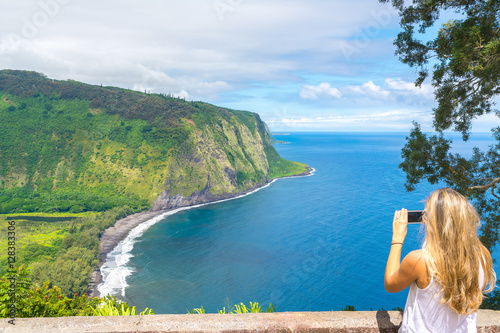 Young woman taking pictures of the amazing view in Waipio Valley, Big Island, Hawaii, Usa