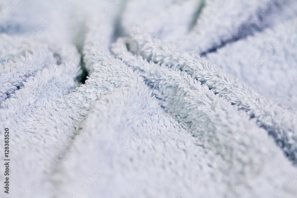 Closeup view of blue towel. Fluffy white background