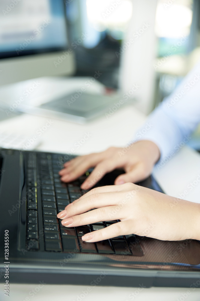 Close-up image of a woman's hands typing on her computer keyboard while sitting at office and working online.