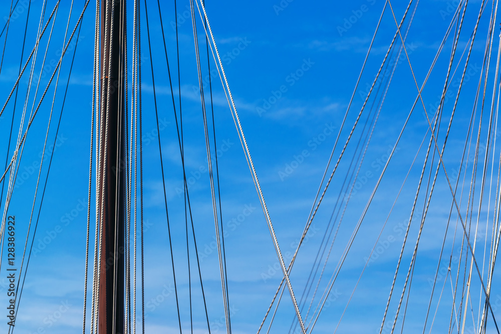 Sailboat mast and ropes in harbor against blue sky Sailboat mast and ropes in harbor against blue sky