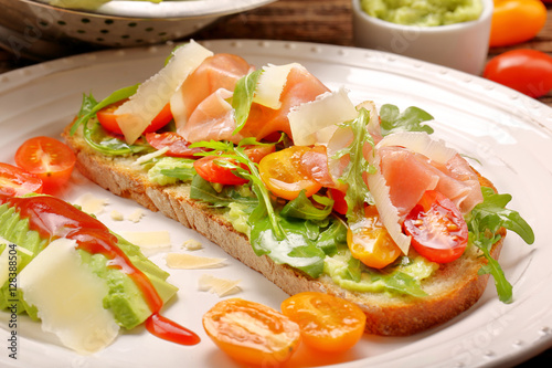 Avocado sandwich on fresh bread with arugula ham tomato and chee