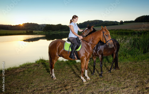 Woman with Two Horses by a Lake at Sunset © courtyardpix