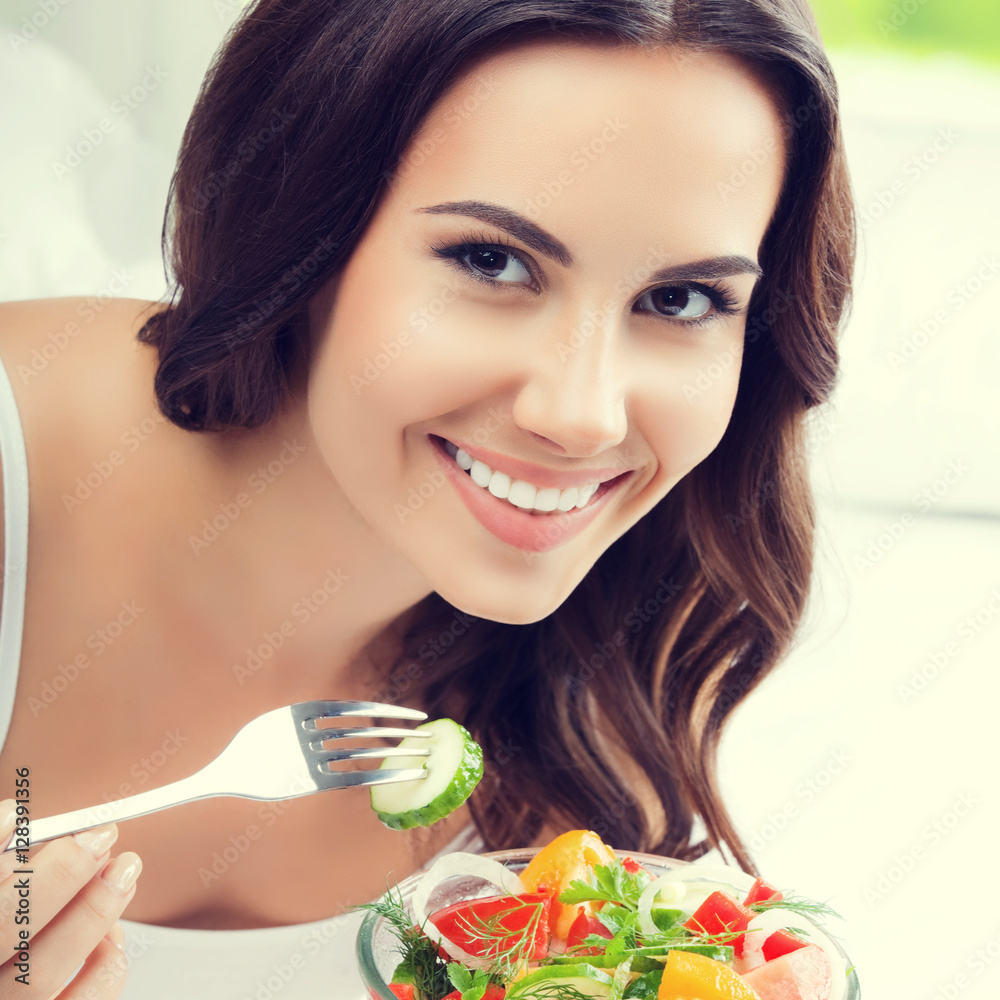 smiling young woman eating salad, on bed smiling young woman eating salad, on bed
